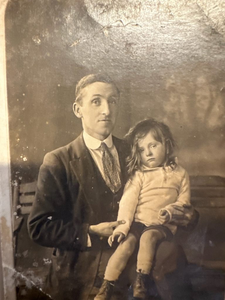 Sepia portrait of William “Bill” O’Shea in a suit he made himself, with his four-year-old son Eddie on his lap, around 1920