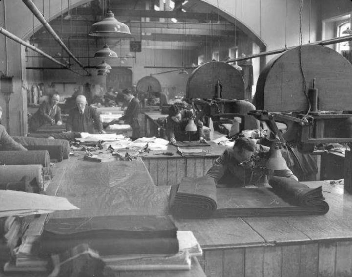 Historic black-and-white photo of cutters at long tables with bolts of cloth and band knives in the Limerick Clothing Factory cutting room